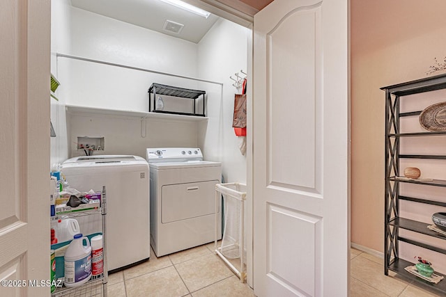 washroom featuring laundry area, light tile patterned floors, visible vents, and washing machine and clothes dryer