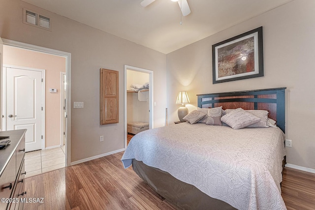 bedroom featuring baseboards, visible vents, ceiling fan, and light wood finished floors