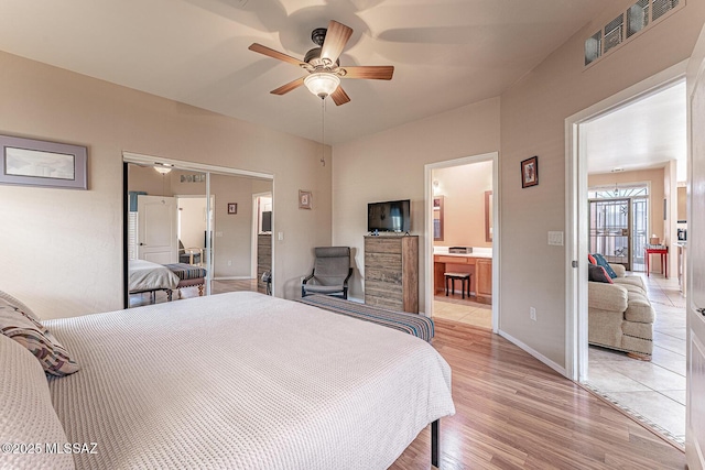 bedroom with visible vents, baseboards, ensuite bath, ceiling fan, and light wood-style floors