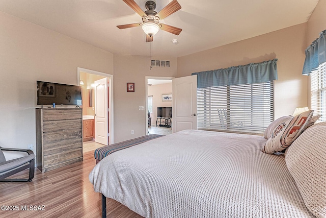 bedroom with light wood finished floors, visible vents, a ceiling fan, connected bathroom, and baseboards