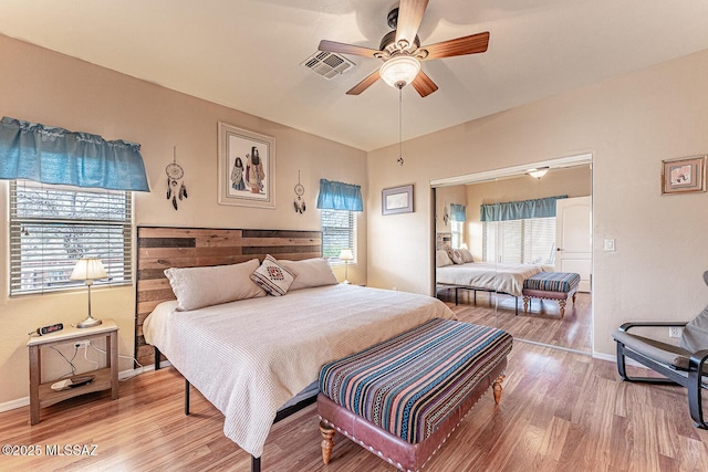 bedroom featuring light wood finished floors, a ceiling fan, visible vents, and baseboards