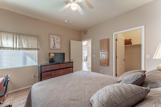 bedroom featuring baseboards, visible vents, a ceiling fan, a spacious closet, and light wood-type flooring