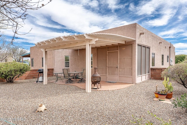 rear view of house featuring an outdoor fire pit, a pergola, a patio, and stucco siding