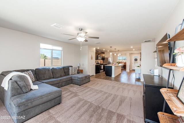 living area featuring a ceiling fan, recessed lighting, visible vents, and light carpet