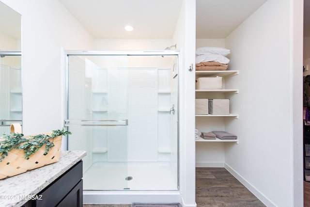 full bath with a stall shower, baseboards, wood finished floors, and vanity