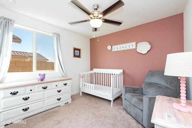 bedroom with light carpet, ceiling fan, and a crib