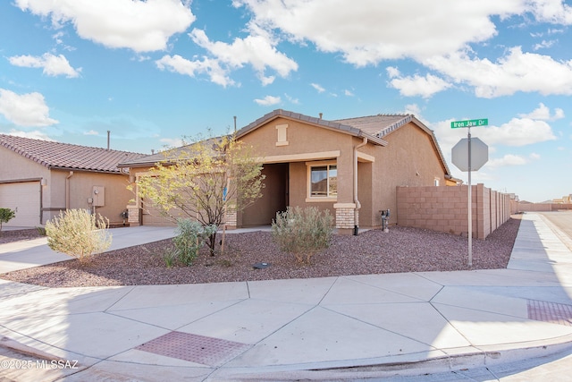 view of front of house with a tile roof, stucco siding, concrete driveway, an attached garage, and fence