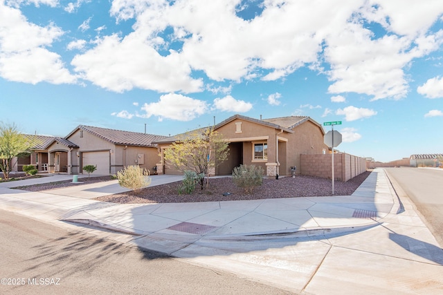 view of front of house with driveway, an attached garage, fence, and stucco siding