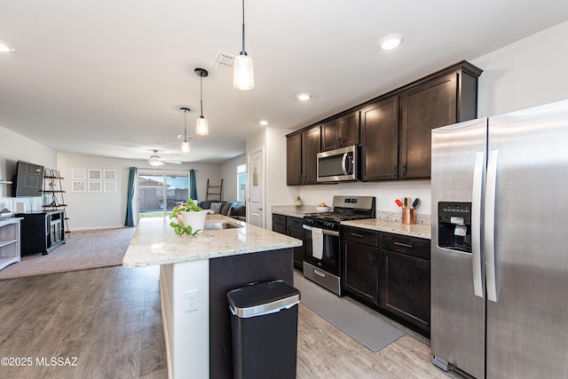 kitchen featuring appliances with stainless steel finishes, open floor plan, dark brown cabinets, and light wood finished floors