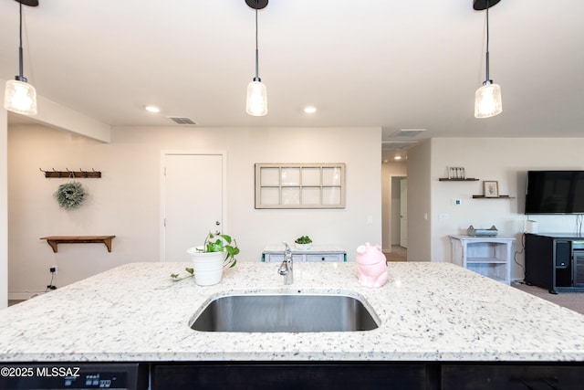 kitchen featuring a center island with sink, visible vents, dishwashing machine, light stone counters, and a sink