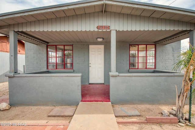 view of exterior entry featuring brick siding and covered porch