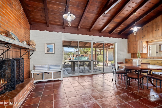 dining space featuring dark tile patterned floors, a fireplace, wood ceiling, and lofted ceiling with beams