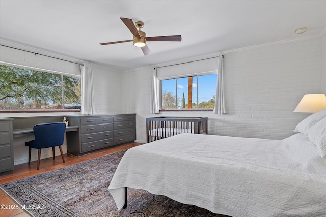 tiled bedroom with multiple windows, brick wall, a ceiling fan, and ornamental molding