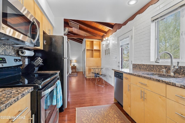 kitchen with dark wood finished floors, vaulted ceiling with beams, a sink, wood ceiling, and appliances with stainless steel finishes