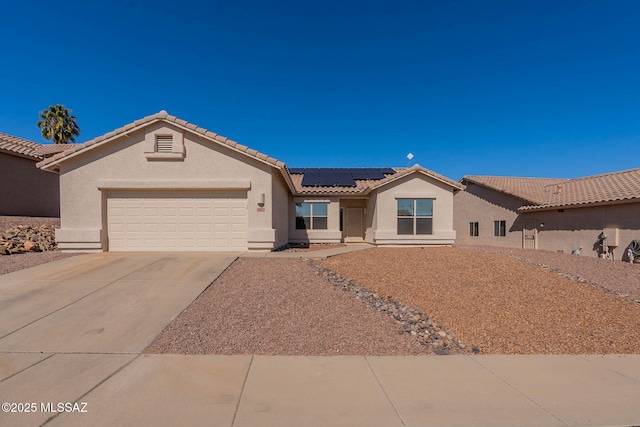 ranch-style home with roof mounted solar panels, a tile roof, concrete driveway, and stucco siding