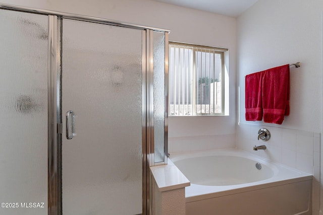 bathroom featuring a shower stall and a bath