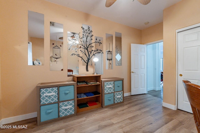 interior space featuring ceiling fan, baseboards, and wood finished floors