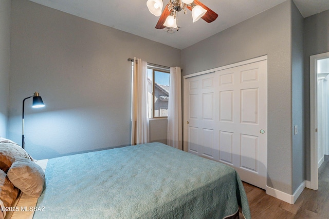 bedroom with ceiling fan, a closet, wood finished floors, and baseboards