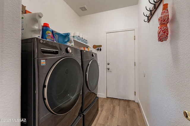 washroom featuring laundry area, baseboards, visible vents, wood finished floors, and independent washer and dryer