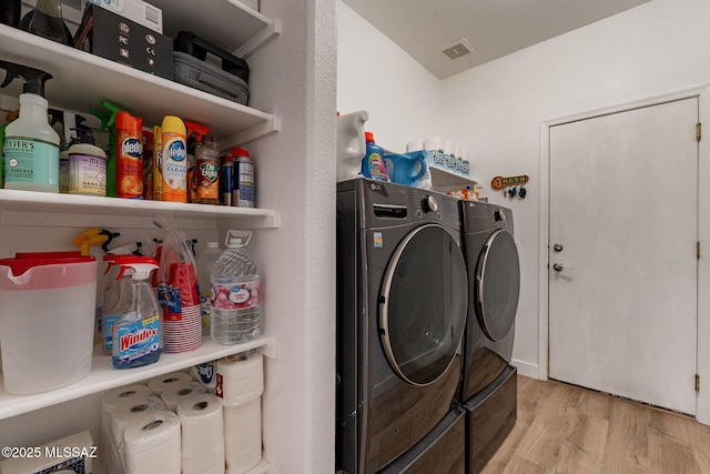 laundry area featuring laundry area, visible vents, wood finished floors, and washing machine and clothes dryer