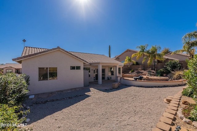 back of house with a patio area, a tiled roof, fence, and stucco siding