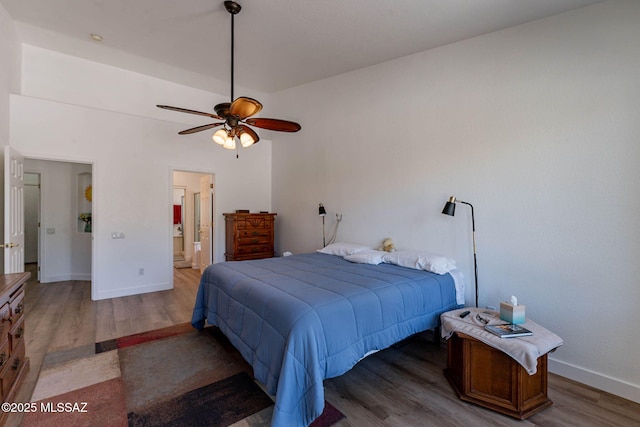 bedroom with ensuite bathroom, wood finished floors, a ceiling fan, and baseboards