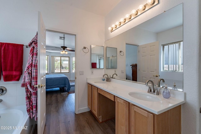 ensuite bathroom featuring double vanity, baseboards, a sink, and wood finished floors