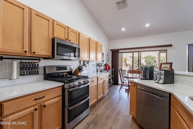 kitchen featuring stainless steel appliances, recessed lighting, visible vents, vaulted ceiling, and wood finished floors