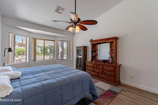 bedroom featuring baseboards, visible vents, ceiling fan, and wood finished floors