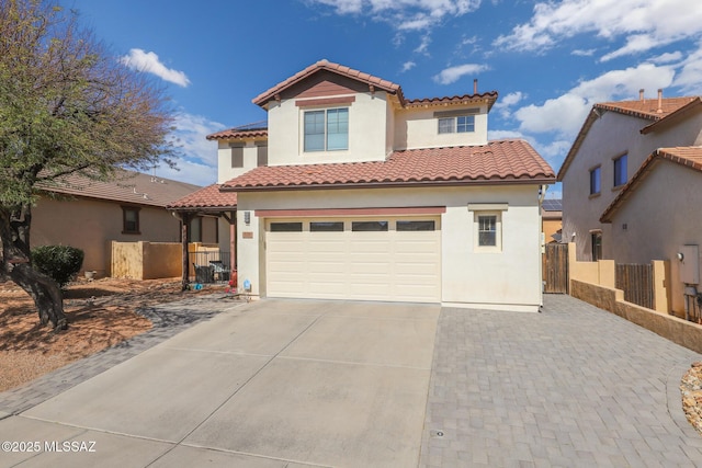 mediterranean / spanish-style home featuring fence, an attached garage, a tile roof, concrete driveway, and stucco siding