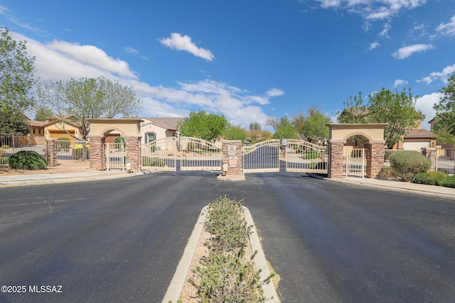 view of road featuring a gate, curbs, and sidewalks