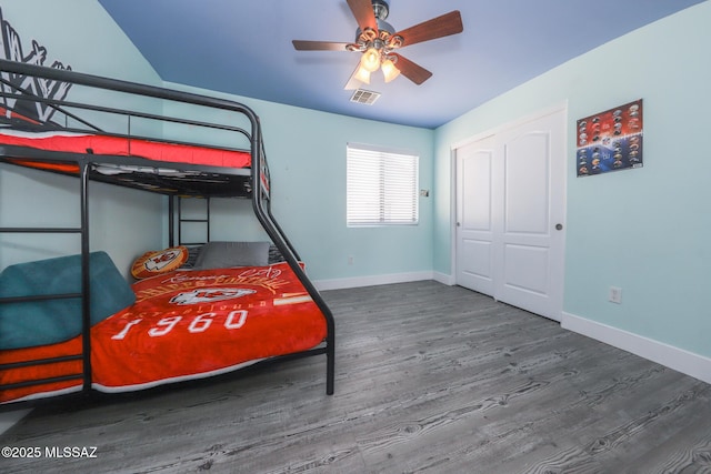 bedroom featuring wood finished floors, a closet, visible vents, baseboards, and ceiling fan