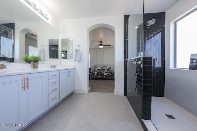 ensuite bathroom with a ceiling fan, a wealth of natural light, walk in shower, and a sink