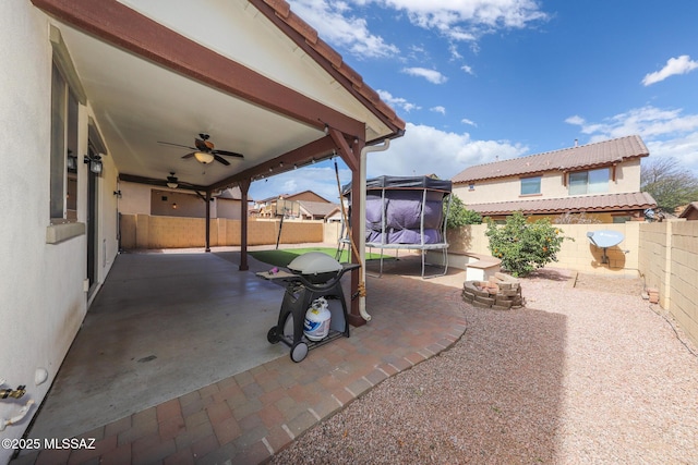 view of patio featuring a trampoline, a ceiling fan, and a fenced backyard
