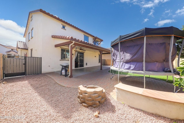 back of house with a gate, a patio, stucco siding, and a tiled roof