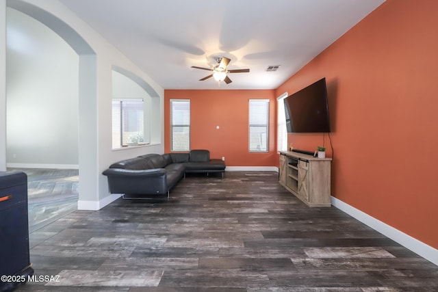 living area with a healthy amount of sunlight, a ceiling fan, visible vents, and dark wood finished floors