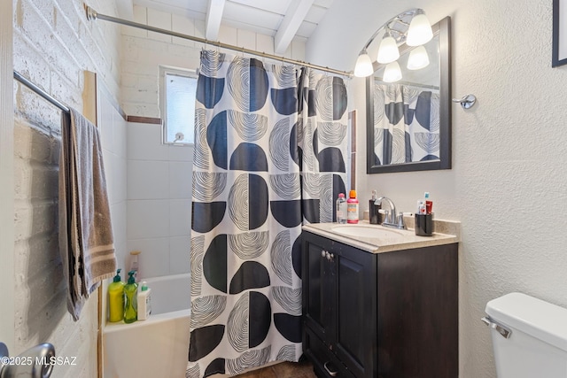 full bathroom with a textured wall, shower / bath combo, vanity, and toilet