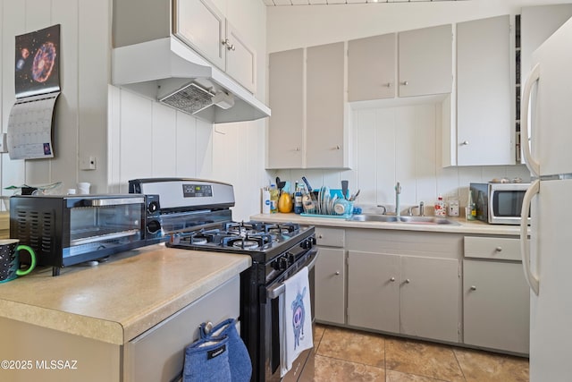 kitchen featuring a toaster, a sink, light countertops, appliances with stainless steel finishes, and range hood