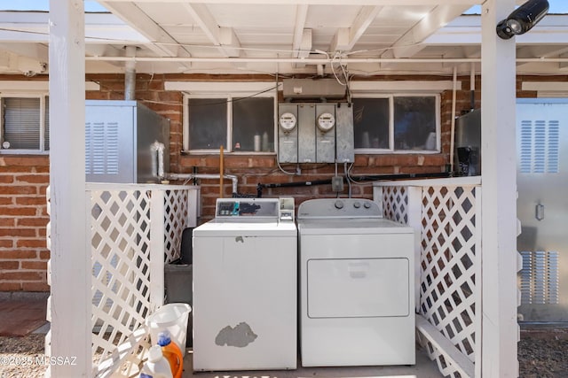 laundry area featuring brick wall, separate washer and dryer, and laundry area