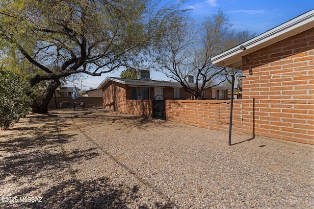 view of side of property featuring fence and brick siding