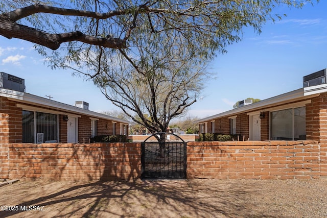 view of home's exterior with a gate, brick siding, fence, and a chimney