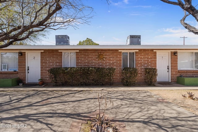 view of front of property with central air condition unit and brick siding