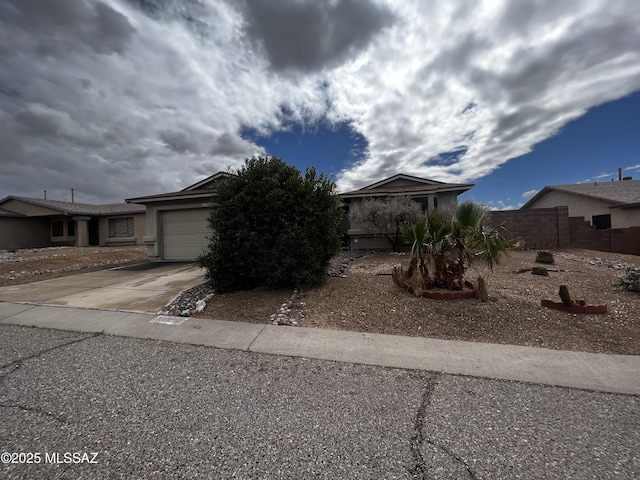 view of front of home featuring a garage, concrete driveway, and fence