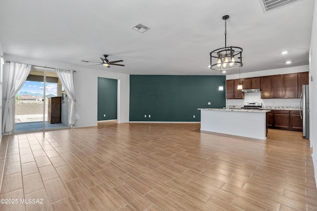 unfurnished living room featuring visible vents, ceiling fan with notable chandelier, baseboards, and light wood-style floors