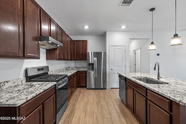 kitchen featuring visible vents, under cabinet range hood, decorative light fixtures, a sink, and appliances with stainless steel finishes