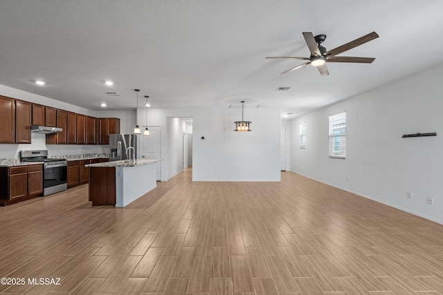 kitchen featuring ceiling fan, light wood-style floors, open floor plan, and stainless steel appliances