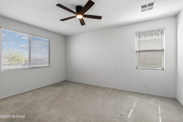 carpeted empty room featuring visible vents, baseboards, and ceiling fan