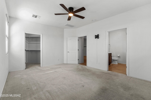 unfurnished bedroom featuring visible vents, carpet flooring, ensuite bath, and a walk in closet