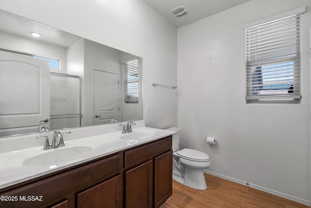 bathroom featuring double vanity, toilet, baseboards, and a sink