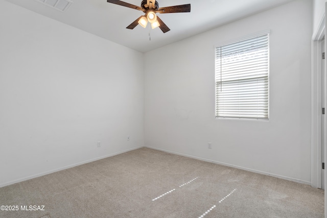 spare room with visible vents, light colored carpet, baseboards, and a ceiling fan